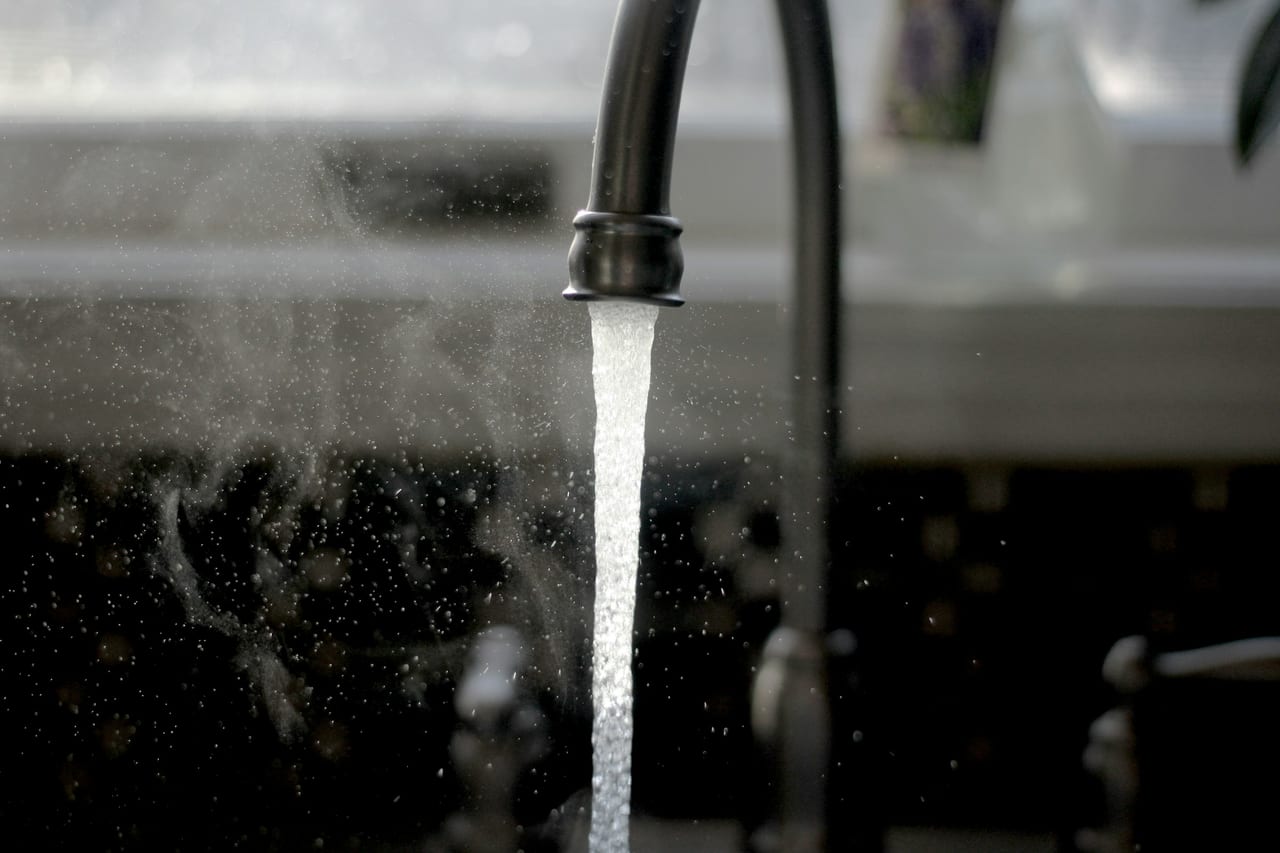 Chrome faucet with running water over a residential sink